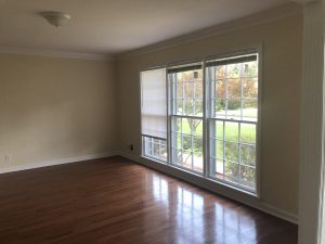 empty living room; red oak floors, wide window cream wall paint; 8-ft ceiling