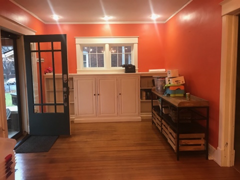 orange wall paint, storage unit in entry way, white cabinets
